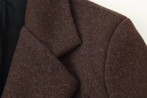 Detailed close-up of dark brown wool coat collar and textured fabric surface