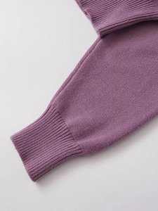 Détail de la manche d'un pull en tricot violet montrant la maille et le poignet côtelé