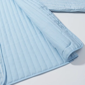 Close-up of light blue quilted jacket fabric showing vertical stitching and striped lining