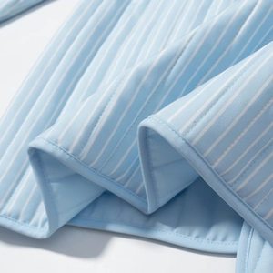 Detail of blue and white striped quilted fabric with soft texture and neat hem binding