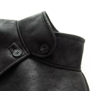 Detail of a chic black faux suede jacket featuring a stand collar and elegant double buttons