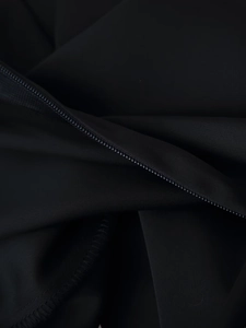 Close-up of high-quality zipper and fine stitching on black satin trousers