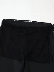 Detailed macro view of black floral lace fabric and drawstring waist of the sarong
