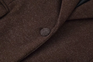 Close-up of wool fabric texture and matching fabric-covered button on a brown coat