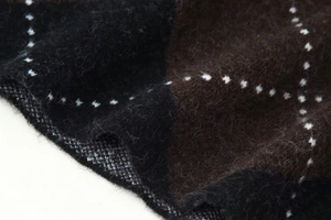 Close-up of diamond pattern knit fabric with black and brown tones and fuzzy texture