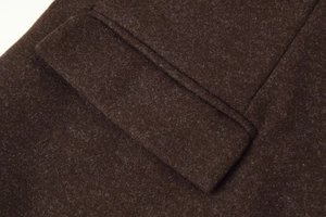 Close-up of deep brown wool coat texture showing flap pocket and neat stitching details