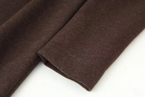 Detailed close-up of dark brown wool fabric texture and clean stitched cuff on coat