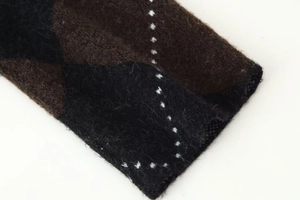 Macro shot of argyle knit fabric texture with dark brown and black diamond pattern