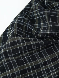 Gros plan détaillé du tissu écossais vert et noir avec des plis doux et des drapés