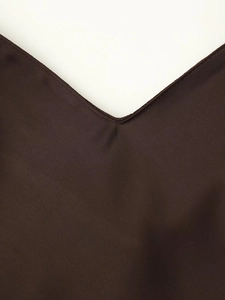 Gros plan sur le tissu en satin marron foncé montrant la texture fine et le col en V