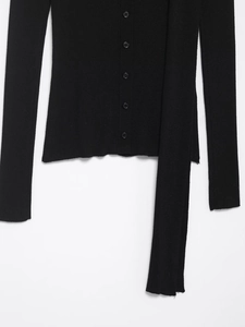 Détail d'un cardigan en maille côtelée noire avec boutons et longue lanière décorative
