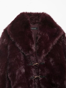 Detail of burgundy faux fur coat with plush lapels and metal lobster buckle closures