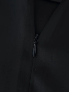 Detailed macro view showing the high-quality invisible zipper on black satin trousers
