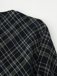 Gros plan du tissu à carreaux noir et vert montrant la couture et la texture tissée