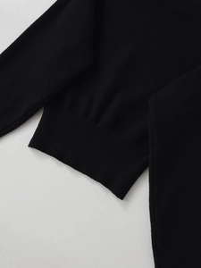 Détail du poignet en tricot côtelé et de la texture noire lisse sur ce pull pour femme
