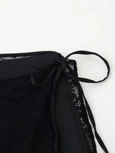 Detailed close-up of delicate black floral lace texture with elegant silk side tie detail