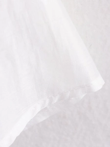 Macro shot of fine stitching and hem detail on white cotton embroidered shirt
