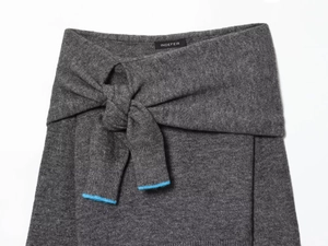 Detail of grey knit fabric with wrap-around knot design and bright blue piping edge
