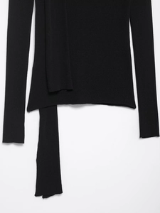 Détail du cardigan en maille côtelée noire avec longues lanières latérales et texture douce