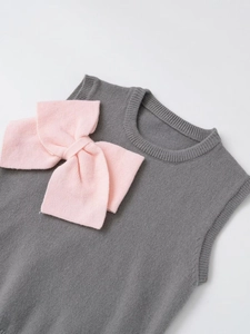 Detail of grey knit vest featuring a large soft pink bow decoration with fine texture
