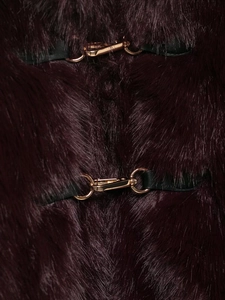 Detailed macro view of dark purple faux fur coat with golden metal clasp and leather strap