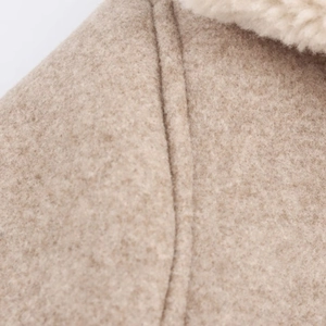 Dettaglio macro della trama in lana beige e del collo in ecopelliccia bianca della giacca