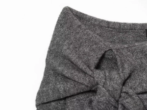 Detail shot of a dark grey knit sweater featuring a stylish knotted twist design