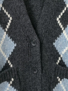 Detail of argyle knit cardigan showing grey and blue diamond pattern and soft texture