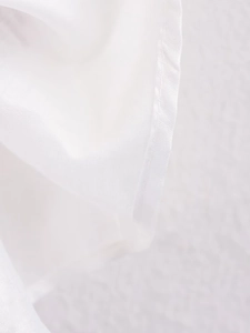 Close-up of white embroidered shirt sleeve showing fine rolled hem and lightweight fabric