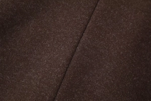 Detailed close-up of dark brown wool coat fabric texture and high-quality stitching work