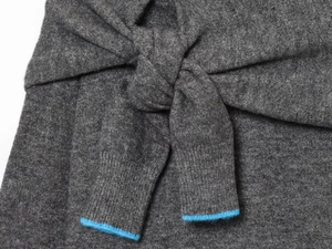 Detail of dark grey knitwear featuring knot design and blue contrast edge trim