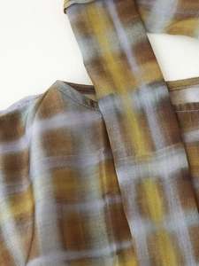 Detail of checkered plaid pattern in yellow and brown tones on light woven fabric