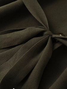 Detail view of dark green knitted cardigan showing elegant pleats and matching resin button
