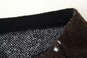 Close-up detail of knitted sweater showing black ribbed cuffs and grey wool texture