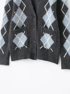 Detail of argyle knit cardigan featuring V-neckline, dark buttons and side pockets