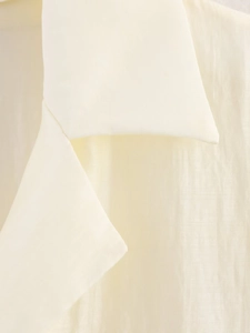 Macro detail of creamy beige textured fabric showing fine vertical lines and soft silk sheen