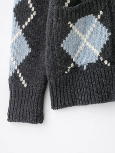 Close-up of argyle knit cardigan showing grey and blue pattern with ribbed cuffs