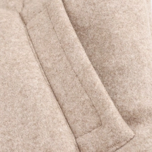 Dettaglio ravvicinato della giacca di lana con cuciture precise e tessuto beige morbido