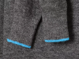 Detail shot of dark grey knit sleeves with bright blue contrasting ribbed cuffs