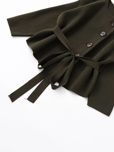Detail of dark green knit cardigan featuring matching waist belt and brown buttons
