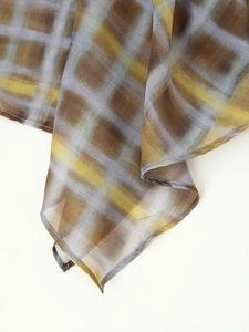 Détail de l'écharpe en tissu à carreaux translucide avec bords ourlés en marron et jaune