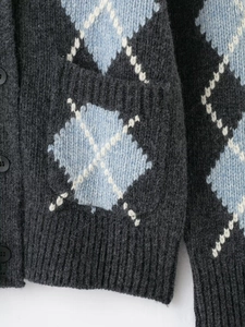 Close-up of grey argyle knit cardigan featuring black button detail and fuzzy texture