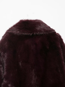 Close-up of deep burgundy faux fur coat showing dense texture and soft glossy finish