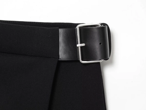 Détail de large ceinture en cuir noir avec boucle carrée argentée sur un pantalon