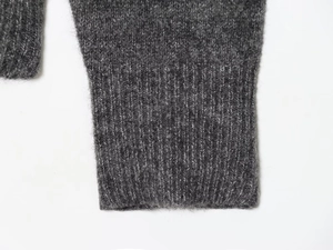 Detailed macro view of dark grey fuzzy knit fabric showing ribbed cuffs and wool texture