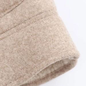 Dettaglio macro della giacca in lana beige con fodera in pile e cuciture rinforzate