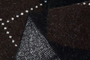 Detailed macro view of dark brown knit fabric with white polka dots and geometric pattern