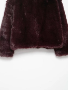 Close-up detail of plush faux fur texture and sleeve hem on a deep burgundy coat