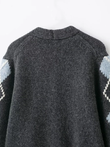 Detail of dark grey knit cardigan with classic argyle patterns on the thick sleeves
