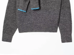 Close-up of ribbed cuffs and hem on dark grey knit sweater with blue stripe detail